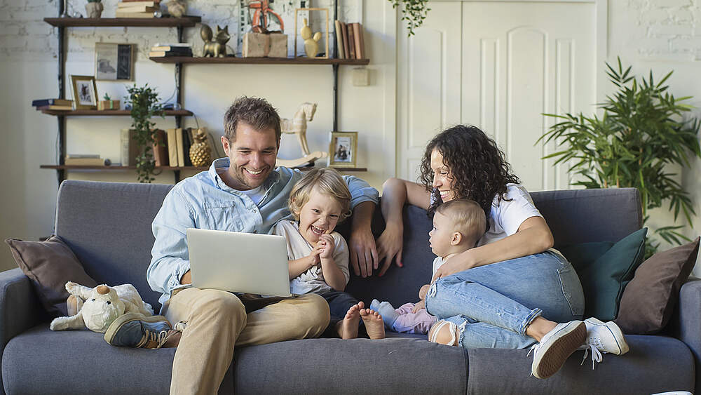© Adobe Stock / Zarya Maxim Eine Familie mit Kindern sitzt auf dem Sofa