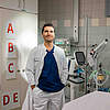 Arzt in Schutzkleidung steht in einem medizinischen Labor vor Geräten.