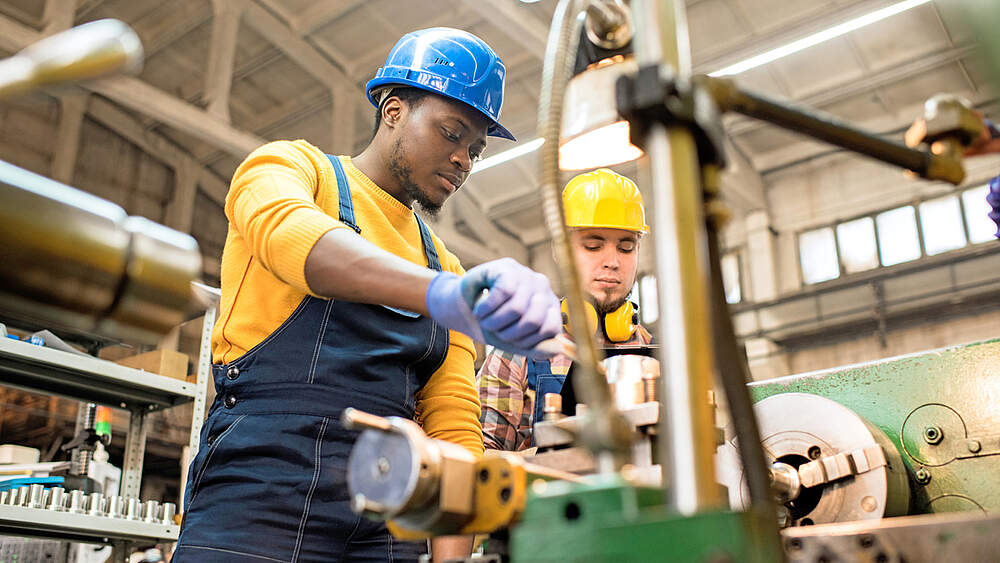 © iStock / SeventyFour Zwei Arbeiter arbeiten mit einer Drehmaschine