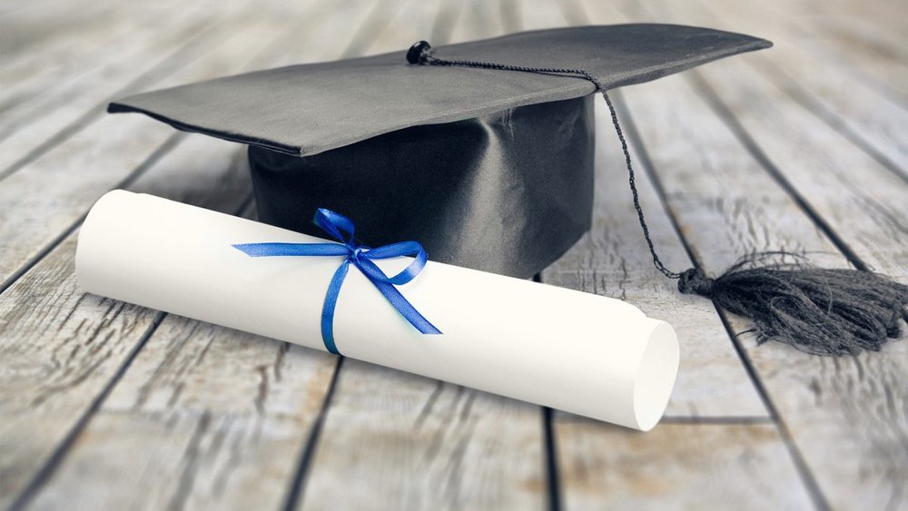 Ein Diplom liegt neben einem Hut auf dem Boden