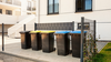 Une rangée de poubelles se trouve devant un nouveau bâtiment.
