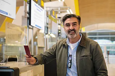 Lächelnder Mann steht in einem modernen Büro mit bunten Akzenten.