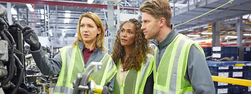 © iStock / Morsa Images Des ingénieurs discutent de pièces automobiles dans une usine.