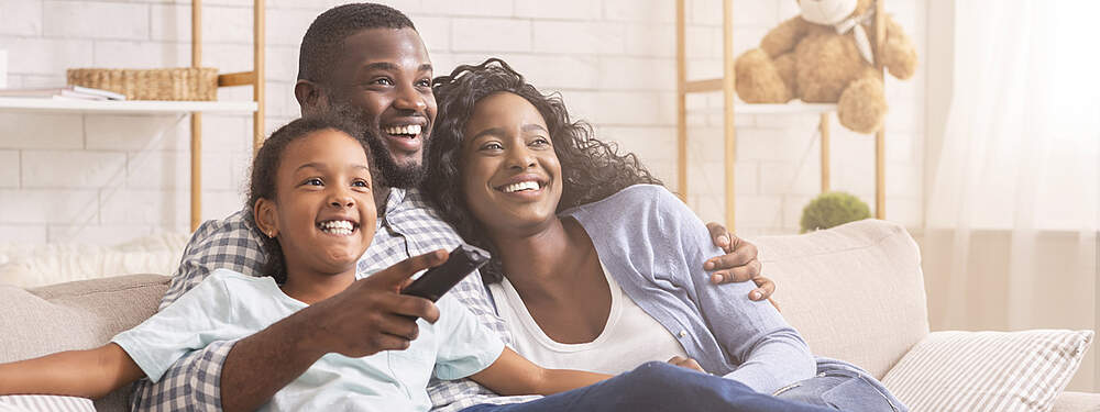 © AdobeStock / Prostock Studio Une famille heureuse devant la télévision.
